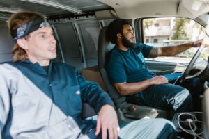 Zwei Mitarbeiter sitzen während einer Fahrt im Transporter