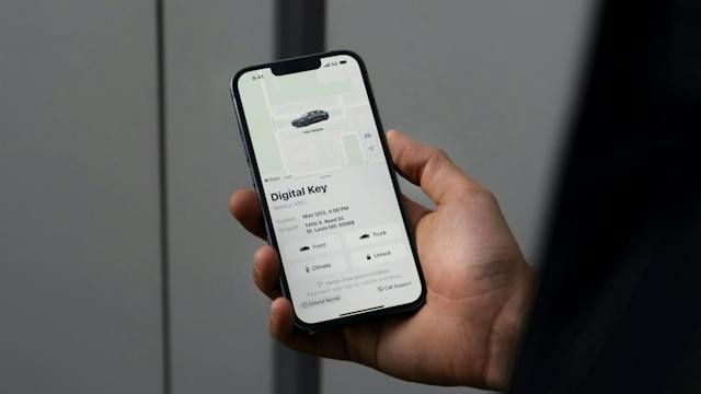 Smartphone mit angezeigtem digitalen Fahrzeugschlüssel in einer Hand