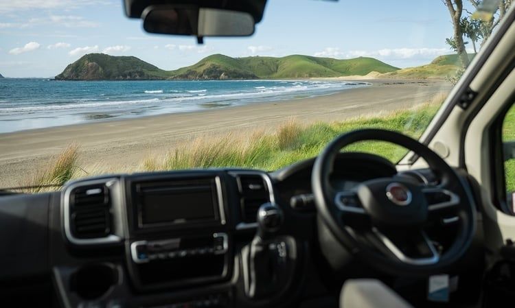 Cockpit eines Reisemobils mit Blick auf einen sandigen Küstenstrand